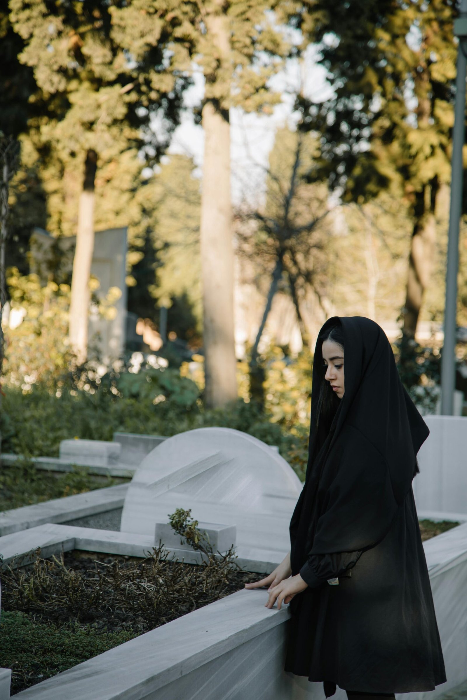 Photo from Pexels by Meruyert Gonullu. A woman stands at a grave in mourning for the dead.
