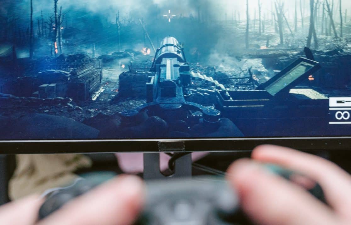 Image from Pexels by Tima Miroshnichenko. A person playing a violent and graphic first-person shooter online game.