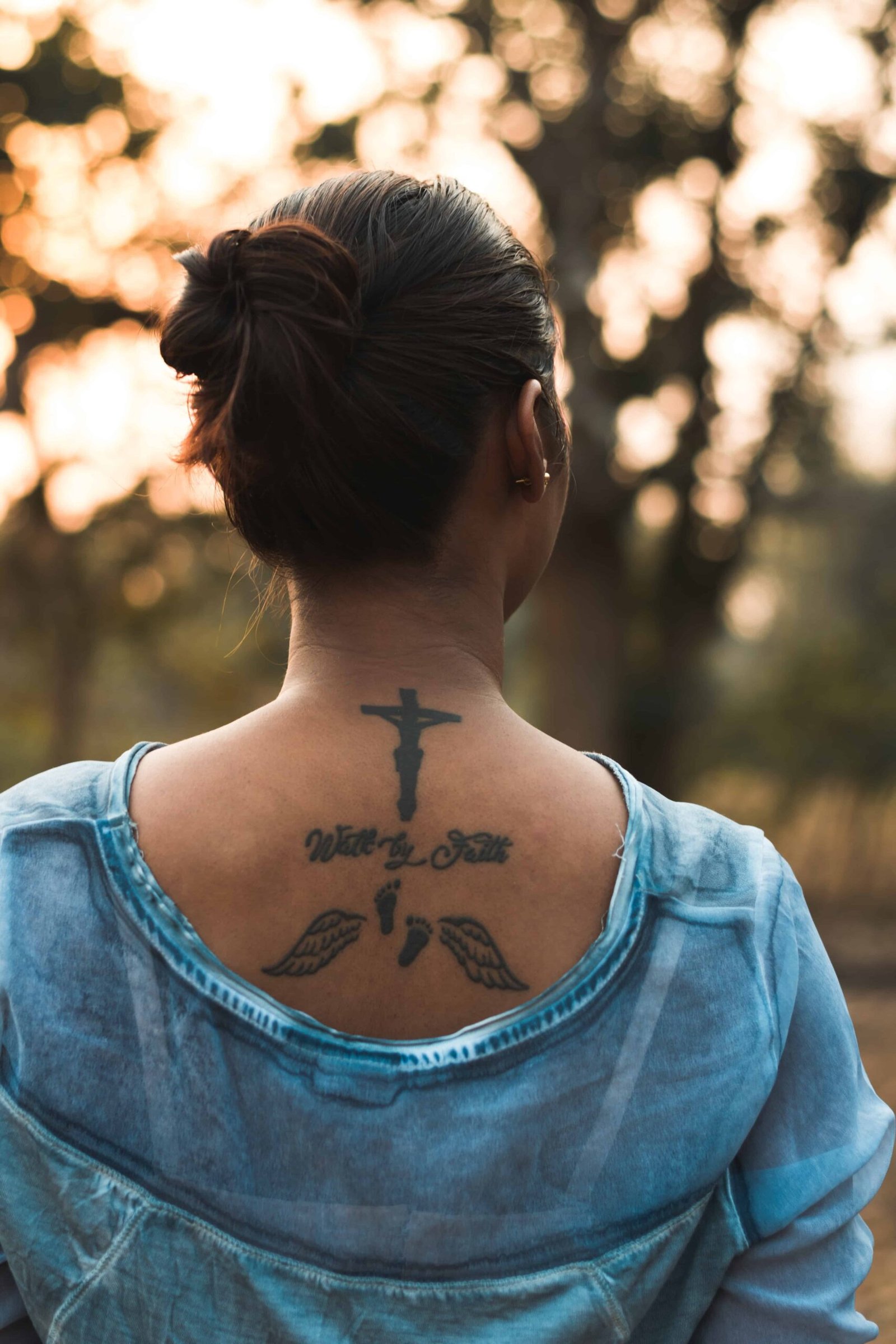 Image from Pexels by Velroy Fernandes. A tattoo of a cross on the neck of a woman.